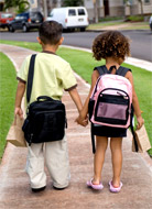 Photo of two small children with backpacks and bag lunches.