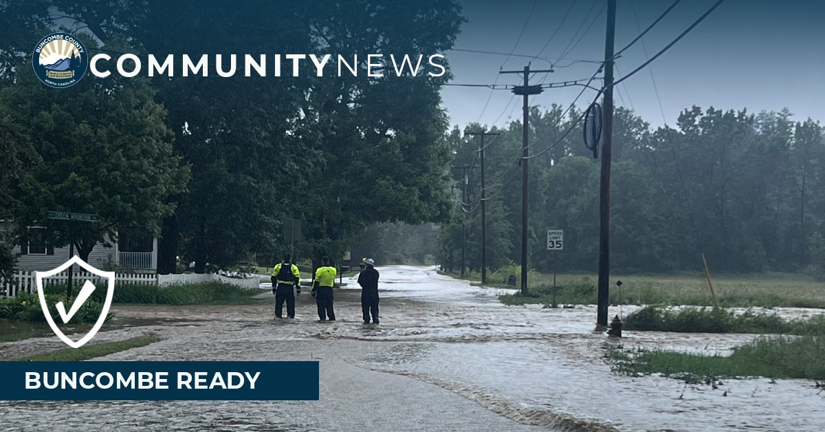 first responders stand at a flooded roadway